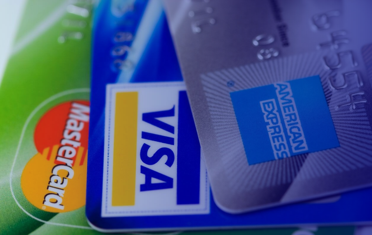 Close-up image of Mastercard, Visa, and American Express credit cards, illustrating the financial concept of credit card delinquencies in relation to apartment prices.